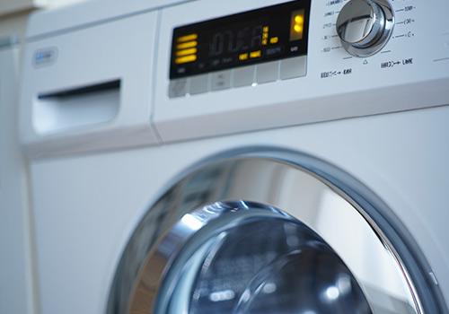 A close-up of a modern washing machine with a digital display showing the word "ON," indicating it is in operation.